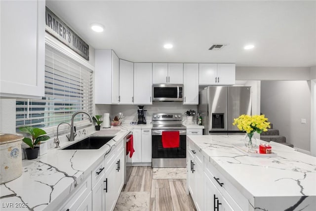 7135 Polaris Ave, Las Vegas, NV 89118 - kitchen featuring appliances with stainless steel finishes, white cabinets, light stone counters, a kitchen island, and recessed lighting