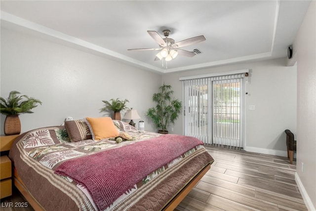 7135 Polaris Ave, Las Vegas, NV 89118 - bedroom featuring wood finished floors, a tray ceiling, ceiling fan, and access to exterior
