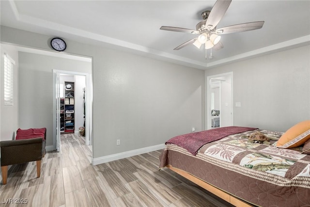 7135 Polaris Ave, Las Vegas, NV 89118 - bedroom featuring a raised ceiling, light wood finished floors, a ceiling fan, and a spacious closet
