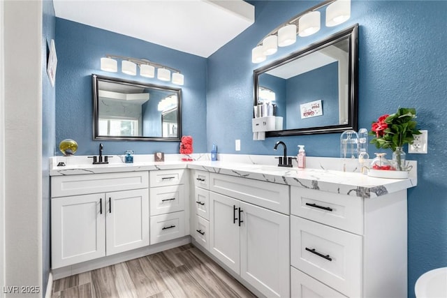 7135 Polaris Ave, Las Vegas, NV 89118 - bathroom featuring a textured wall, double vanity, and wood finished floors