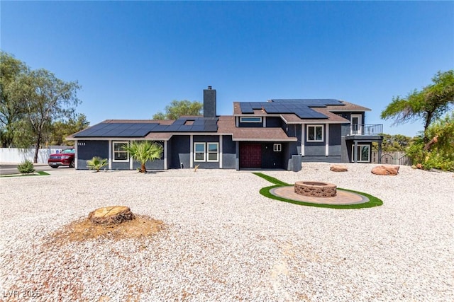 7135 Polaris Ave, Las Vegas, NV 89118 - rear view of property featuring a fire pit, solar panels, a chimney, and a balcony