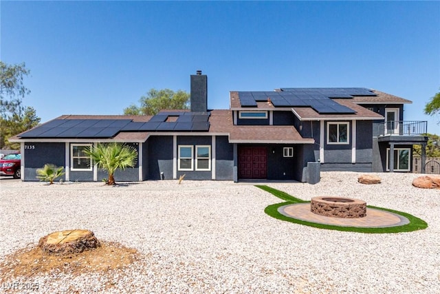 7135 Polaris Ave, Las Vegas, NV 89118 - view of front of house featuring a fire pit, a chimney, roof mounted solar panels, a balcony, and a garage