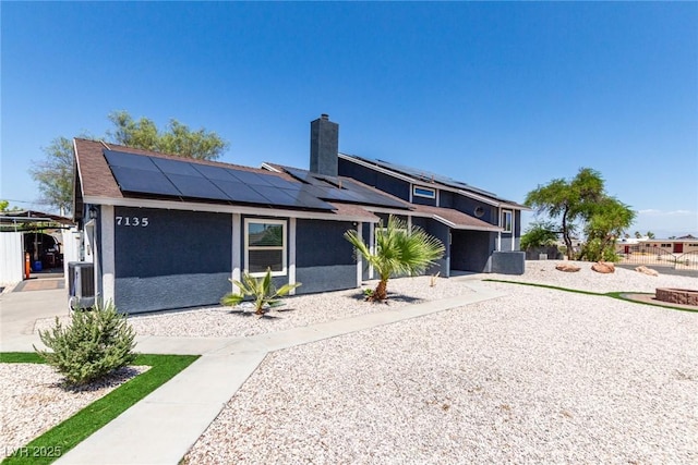 7135 Polaris Ave, Las Vegas, NV 89118 - view of front facade featuring roof mounted solar panels, a chimney, and stucco siding