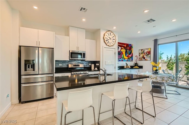 3194 Lumassina Way, Henderson, NV 89044 - kitchen featuring stainless steel appliances, a breakfast bar, dark countertops, decorative backsplash, and an island with sink