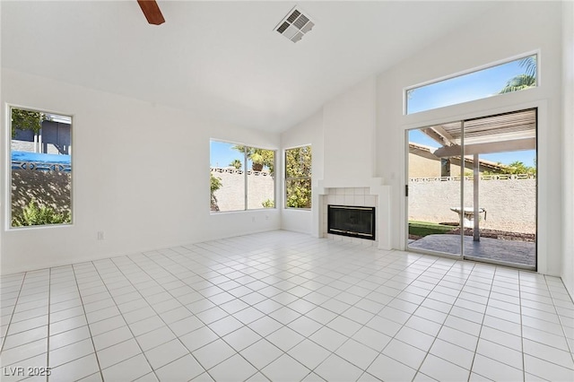 1908 Summit Pointe Dr, Las Vegas, NV 89117 - unfurnished living room featuring light tile patterned floors, a tiled fireplace, healthy amount of natural light, high vaulted ceiling, and ceiling fan