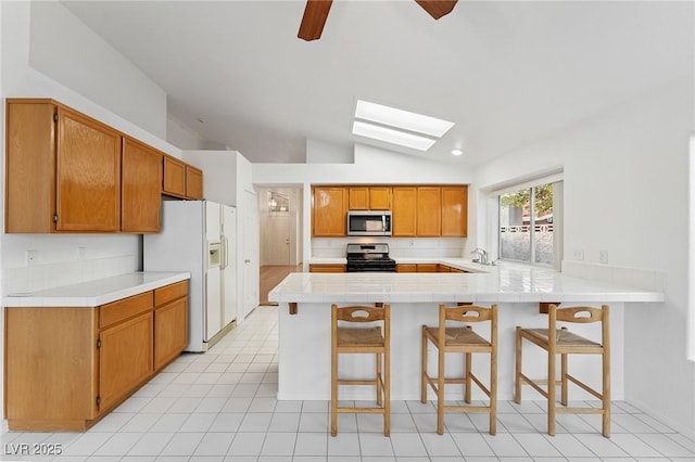 1908 Summit Pointe Dr, Las Vegas, NV 89117 - kitchen featuring appliances with stainless steel finishes, a peninsula, a skylight, vaulted ceiling, and tasteful backsplash