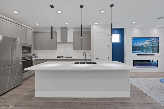 9617 Sard Ln, Las Vegas, NV 89143 - kitchen featuring appliances with stainless steel finishes, wall chimney exhaust hood, gray cabinetry, a glass covered fireplace, and recessed lighting