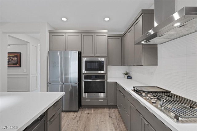 9617 Sard Ln, Las Vegas, NV 89143 - kitchen with appliances with stainless steel finishes, wall chimney range hood, gray cabinetry, light wood-style flooring, and light countertops