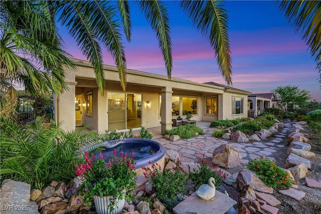 1637 Wellington Springs Ave, Henderson, NV 89052 - back of property at dusk featuring a hot tub, stucco siding, and a patio