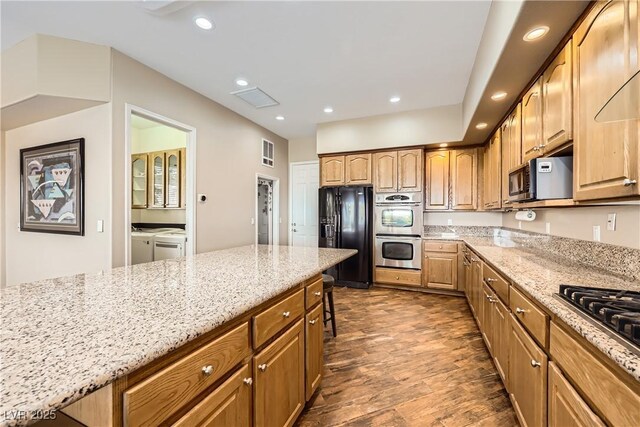 1637 Wellington Springs Ave, Henderson, NV 89052 - kitchen featuring appliances with stainless steel finishes, separate washer and dryer, dark wood finished floors, light stone countertops, and recessed lighting