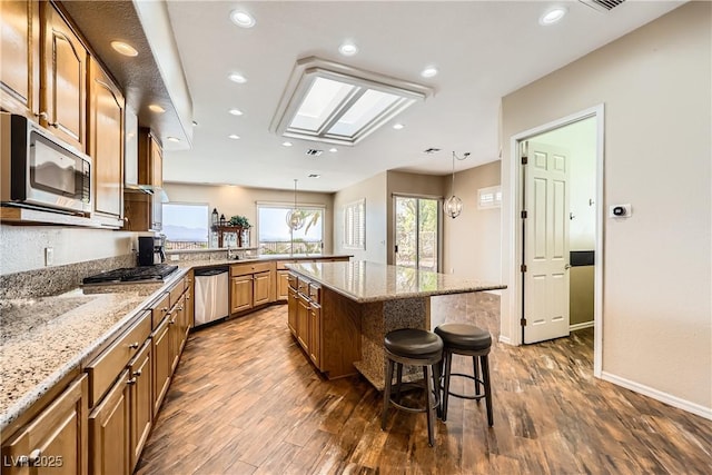 1637 Wellington Springs Ave, Henderson, NV 89052 - kitchen featuring appliances with stainless steel finishes, a breakfast bar area, dark wood-style flooring, light stone countertops, and recessed lighting