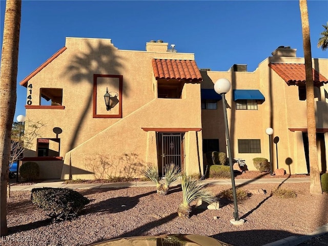 4140 Gannet Cir Unit 251, Las Vegas, NV 89103 - pueblo-style house featuring a chimney, stucco siding, and a tiled roof
