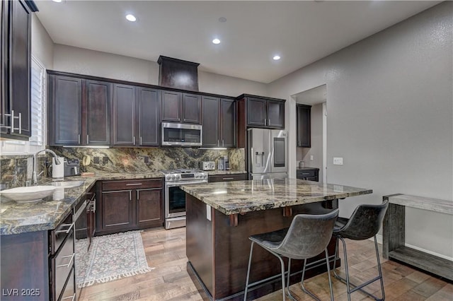 10360 Pescado Ln, Las Vegas, NV 89135 - kitchen featuring stainless steel appliances, light wood-style floors, backsplash, dark stone counters, and a kitchen breakfast bar