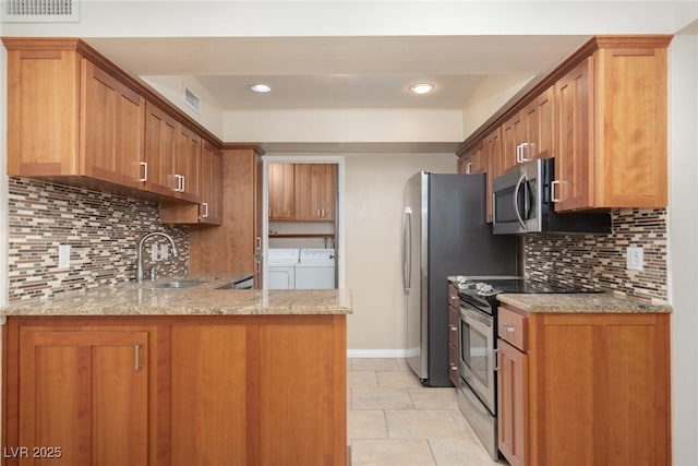 3189 Pinehurst Dr Unit B, Las Vegas, NV 89109 - kitchen with stainless steel appliances, washer and clothes dryer, a peninsula, light stone counters, and decorative backsplash