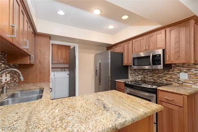3189 Pinehurst Dr Unit B, Las Vegas, NV 89109 - kitchen featuring appliances with stainless steel finishes, washing machine and clothes dryer, a peninsula, light stone countertops, and decorative backsplash