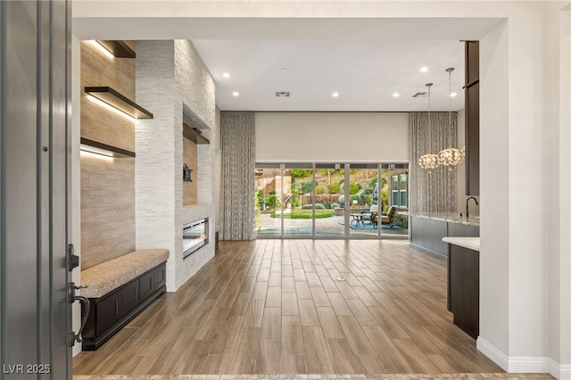 10179 Emerald Sunset Ct, Las Vegas, NV 89148 - living room with a towering ceiling, wood finished floors, a large fireplace, recessed lighting, and a chandelier
