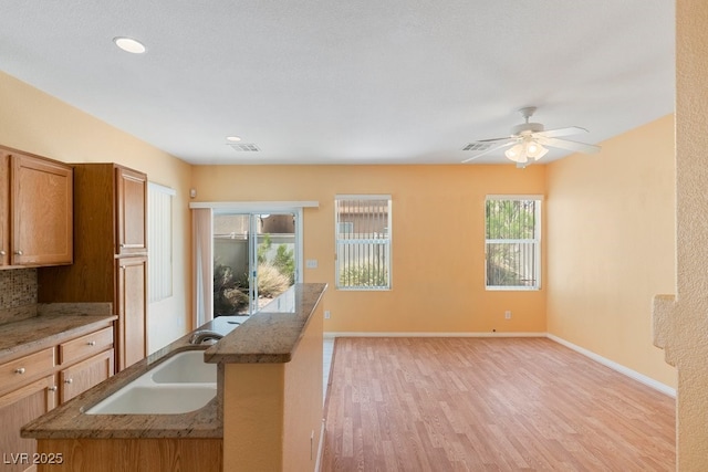 8448 Quarentina Ave, Las Vegas, NV 89149 - kitchen featuring light wood-type flooring, stone counters, brown cabinetry, a ceiling fan, and recessed lighting