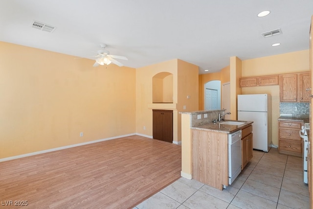 8448 Quarentina Ave, Las Vegas, NV 89149 - kitchen with white appliances, ceiling fan, arched walkways, tasteful backsplash, and light wood-style flooring