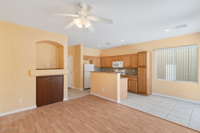 8448 Quarentina Ave, Las Vegas, NV 89149 - kitchen with white appliances, a center island, a ceiling fan, decorative backsplash, and light wood finished floors