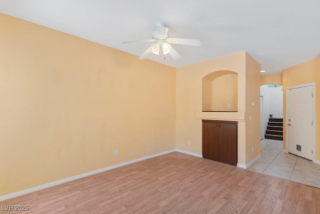 8448 Quarentina Ave, Las Vegas, NV 89149 - spare room featuring light wood-style flooring, ceiling fan, stairs, and arched walkways