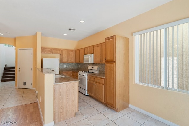 8448 Quarentina Ave, Las Vegas, NV 89149 - kitchen with white appliances, tasteful backsplash, light tile patterned floors, recessed lighting, and light stone counters