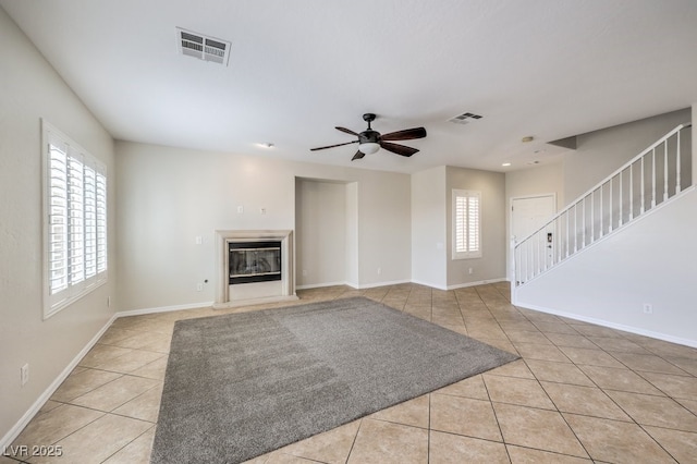 1064 Calvia St, Las Vegas, NV 89138 - unfurnished living room with tile patterned flooring, stairway, a ceiling fan, and a glass covered fireplace