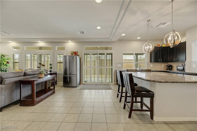 8176 Duncan Peak Ct, Las Vegas, NV 89139 - kitchen with freestanding refrigerator, a chandelier, light tile patterned floors, stone counters, and recessed lighting