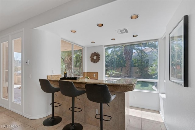 8825 Rozetta Ct, Las Vegas, NV 89134 - kitchen featuring light tile patterned flooring, a breakfast bar area, plenty of natural light, and recessed lighting