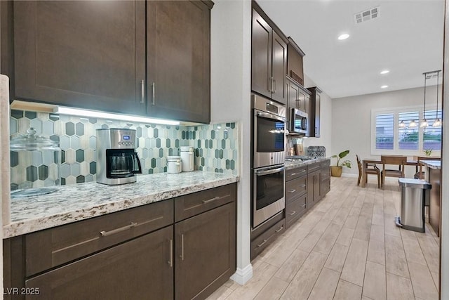 5801 Exbury Gardens Ct, Las Vegas, NV 89118 - kitchen with stainless steel appliances, dark brown cabinetry, decorative backsplash, light wood-style floors, and light stone countertops