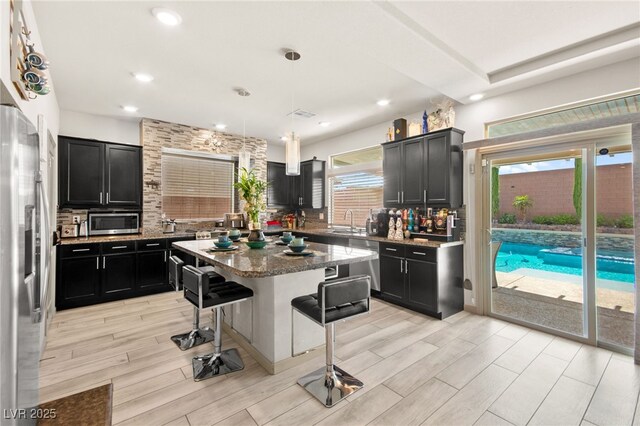 8955 Ruby Moon Dr, Las Vegas, NV 89139 - kitchen with stainless steel appliances, dark cabinetry, backsplash, a breakfast bar area, and stone countertops