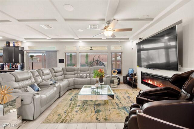 8955 Ruby Moon Dr, Las Vegas, NV 89139 - living area with coffered ceiling, ceiling fan, a glass covered fireplace, beam ceiling, and light wood-style floors