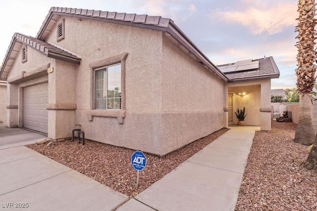 5108 Molveno Ct, Las Vegas, NV 89130 - property exterior at dusk with an attached garage, solar panels, and stucco siding