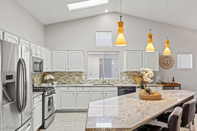 5108 Molveno Ct, Las Vegas, NV 89130 - kitchen featuring stainless steel appliances, light stone counters, a breakfast bar, white cabinetry, and tasteful backsplash