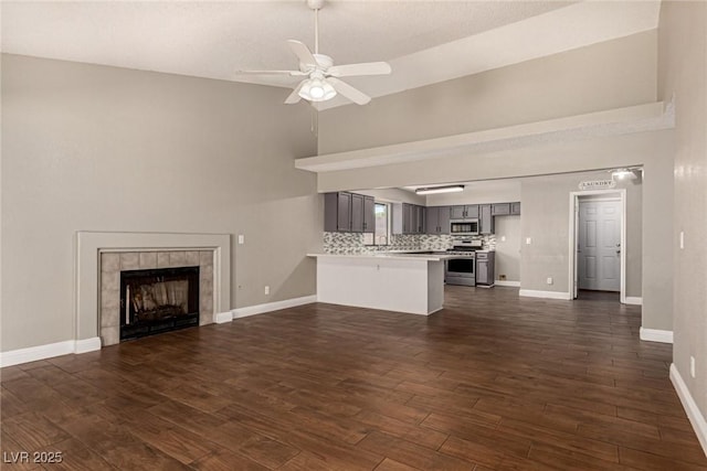 5734 Duval Dr, Las Vegas, NV 89156 - unfurnished living room with ceiling fan, dark wood finished floors, high vaulted ceiling, and a tile fireplace
