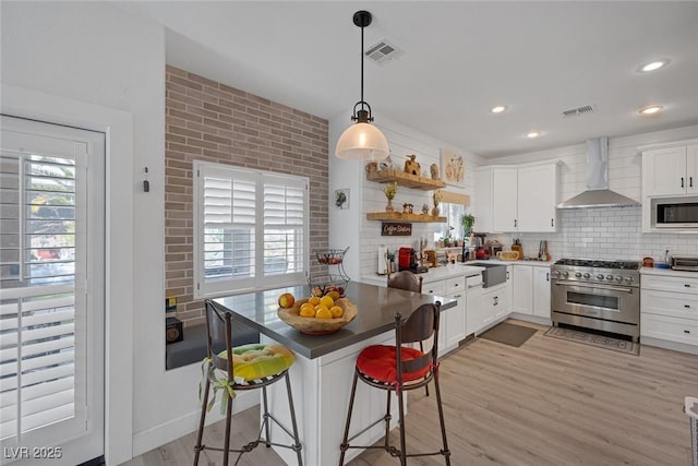 1246 Diamond Valley St, Henderson, NV 89052 - kitchen with high end range, wall chimney range hood, built in microwave, light wood-style floors, and a kitchen breakfast bar