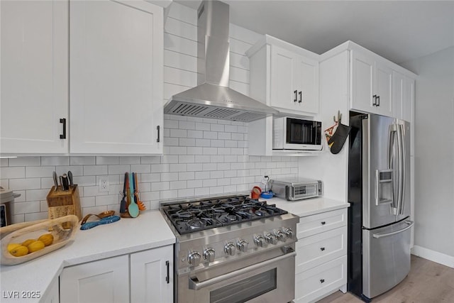 1246 Diamond Valley St, Henderson, NV 89052 - kitchen with appliances with stainless steel finishes, wall chimney exhaust hood, white cabinetry, light countertops, and light wood-type flooring