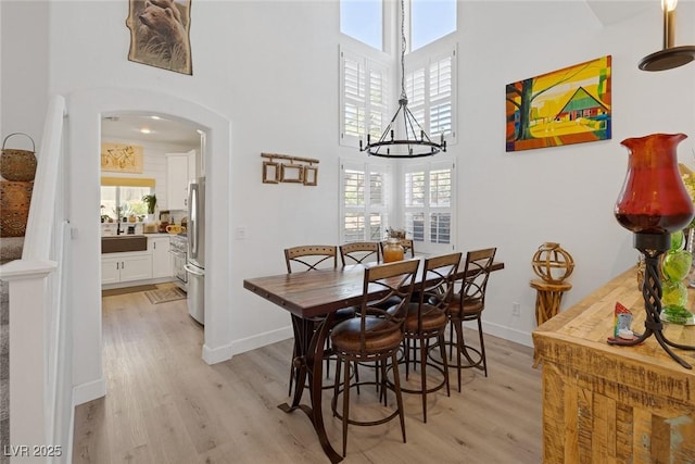 1246 Diamond Valley St, Henderson, NV 89052 - dining room featuring arched walkways, light wood-style flooring, a high ceiling, plenty of natural light, and a chandelier
