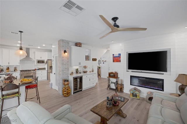 1246 Diamond Valley St, Henderson, NV 89052 - living room featuring wine cooler, a ceiling fan, light wood-style flooring, recessed lighting, and a glass covered fireplace
