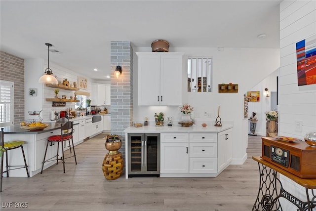 1246 Diamond Valley St, Henderson, NV 89052 - kitchen with wine cooler, light wood-style floors, white cabinets, open shelves, and a breakfast bar