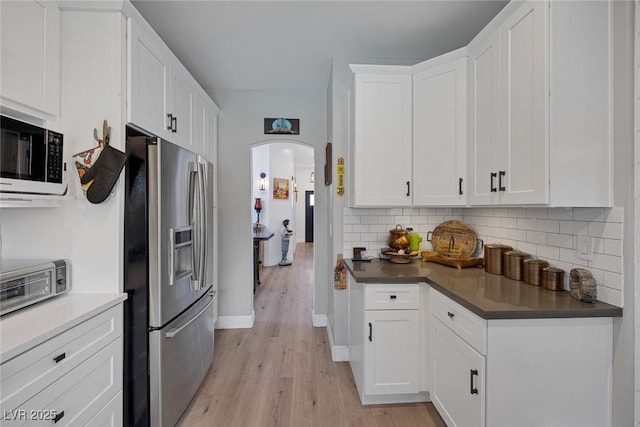 1246 Diamond Valley St, Henderson, NV 89052 - kitchen with stainless steel fridge, white microwave, arched walkways, light wood-type flooring, and tasteful backsplash