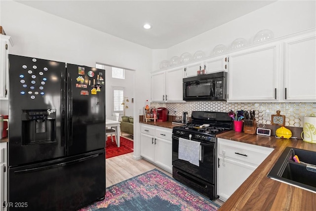 9105 Chenin Ave, Las Vegas, NV 89129 - kitchen featuring black appliances, wooden counters, white cabinets, light wood-type flooring, and decorative backsplash