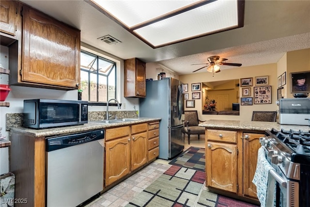3877 Platis Cir, Las Vegas, NV 89103 - kitchen with appliances with stainless steel finishes, a ceiling fan, open floor plan, brown cabinetry, and light countertops