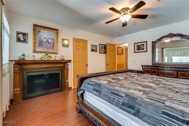 3877 Platis Cir, Las Vegas, NV 89103 - bedroom with wood finished floors, a glass covered fireplace, and ceiling fan