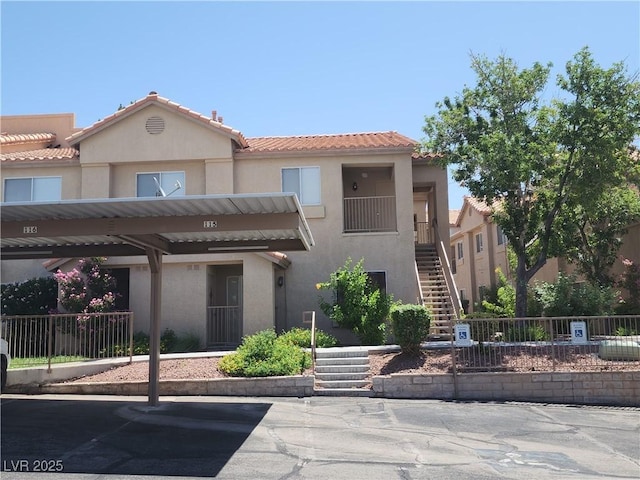 2110 Los Feliz St Unit 1096, Las Vegas, NV 89156 - view of front of house featuring stairway, stucco siding, covered parking, and a tiled roof