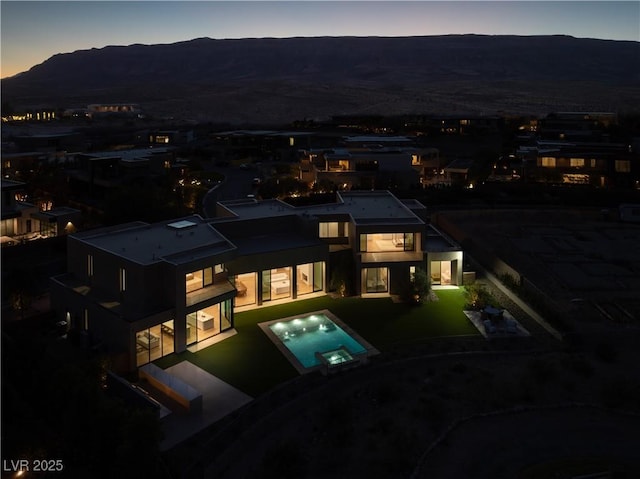 68 Sun Glow Ln, Las Vegas, NV 89135 - back of house at dusk featuring a mountain view, a patio area, and a pool with connected hot tub