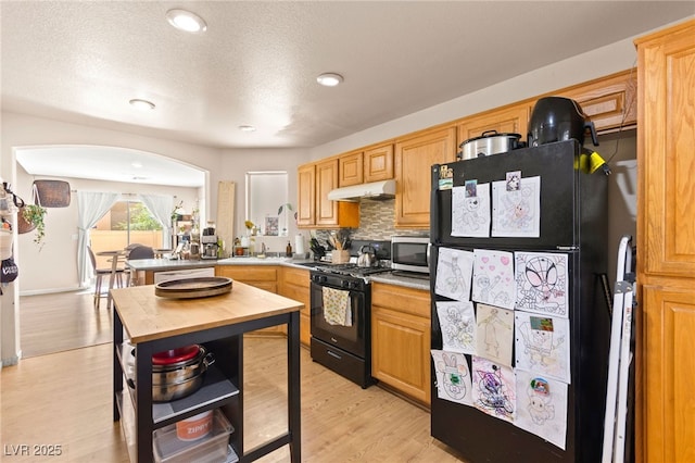 5674 Moccasin Point St, Las Vegas, NV 89148 - kitchen with black appliances, under cabinet range hood, backsplash, wood counters, and light wood-type flooring