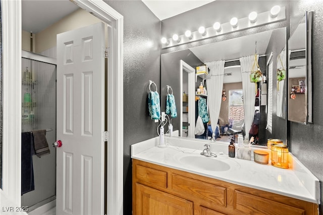 5674 Moccasin Point St, Las Vegas, NV 89148 - bathroom featuring a textured wall, vanity, and a stall shower
