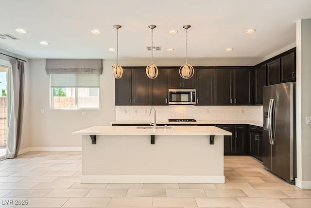 8048 Skye Bridge St, Las Vegas, NV 89166 - kitchen with stainless steel appliances, backsplash, a breakfast bar, light countertops, and a center island with sink