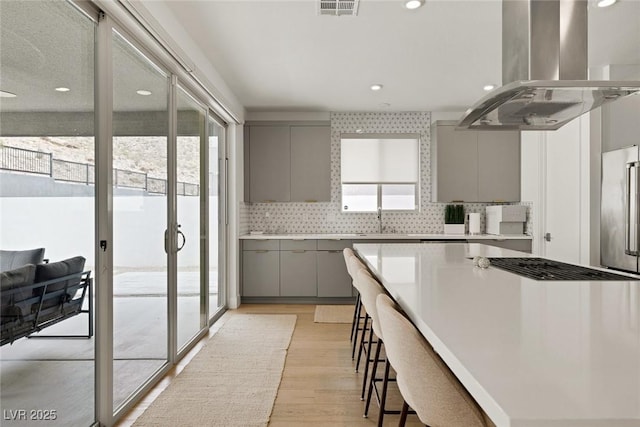 9789 Twilight Moon Ave, Las Vegas, NV 89148 - kitchen featuring gray cabinetry, island exhaust hood, light wood finished floors, backsplash, and recessed lighting
