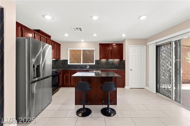 11755 Garland Grove Ln, Las Vegas, NV 89183 - kitchen featuring stainless steel fridge with ice dispenser, black gas stove, dark countertops, reddish brown cabinets, and recessed lighting